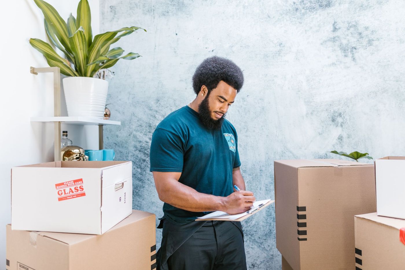A mover noting an inventory on paper in front of a wall of packed cardboard boxes